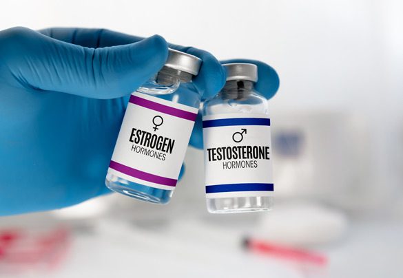 Gloved-hand-holding-vials-of-estrogen-and-testosterone-for-hormone-therapy